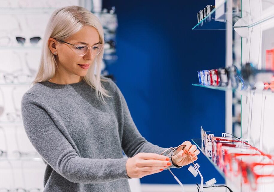 Woman trying on glasses in optometry office, practice management software