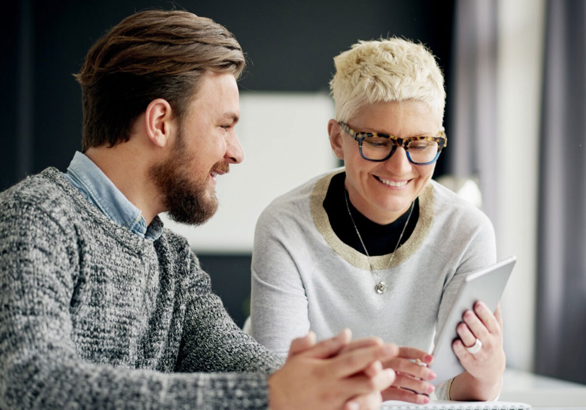 Woman wearing glasses shows male colleague an iPad, eyewear sales